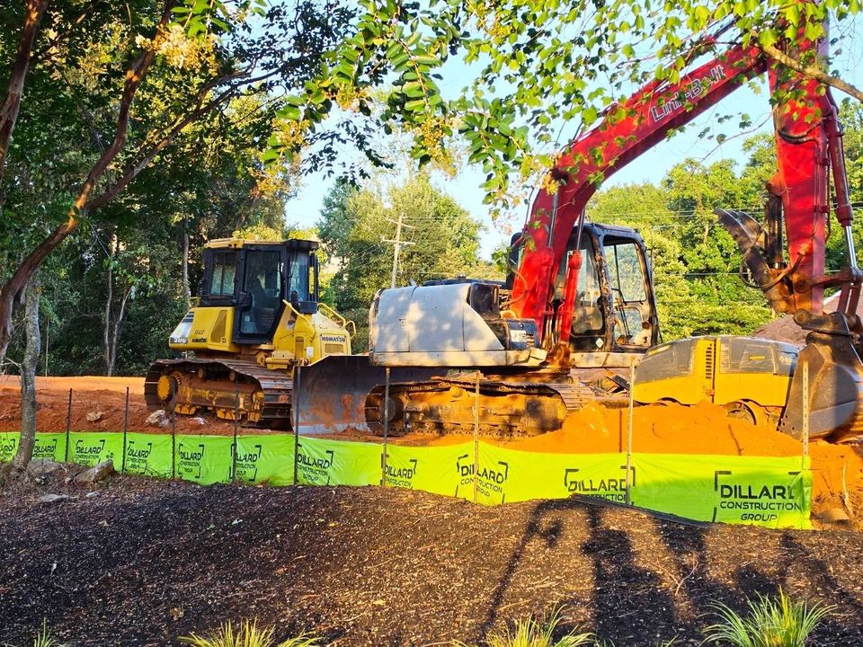 A Dillard Construction Group dozer and excavator behind the company's branded fence wrap after a day of pond grading in Greenville, SC.