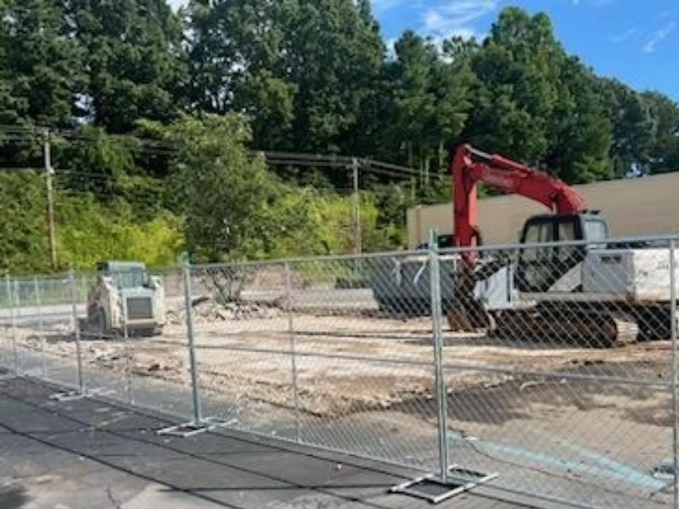 An excavator and skid steer on the cleared site after the building demolition in Easley, SC.